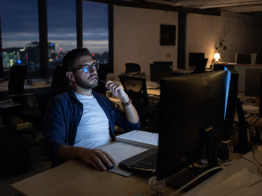Media buyer reviewing campaign performance at his desk after hours